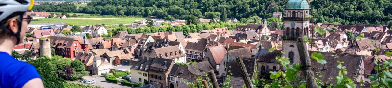 Radfahrer, der die Aussicht auf das Dorf Kaysersberg im Elsass genießt.