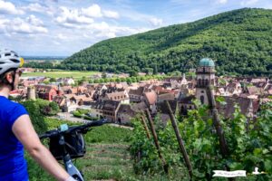 Radfahrer, der die Aussicht auf das Dorf Kaysersberg im Elsass genießt.